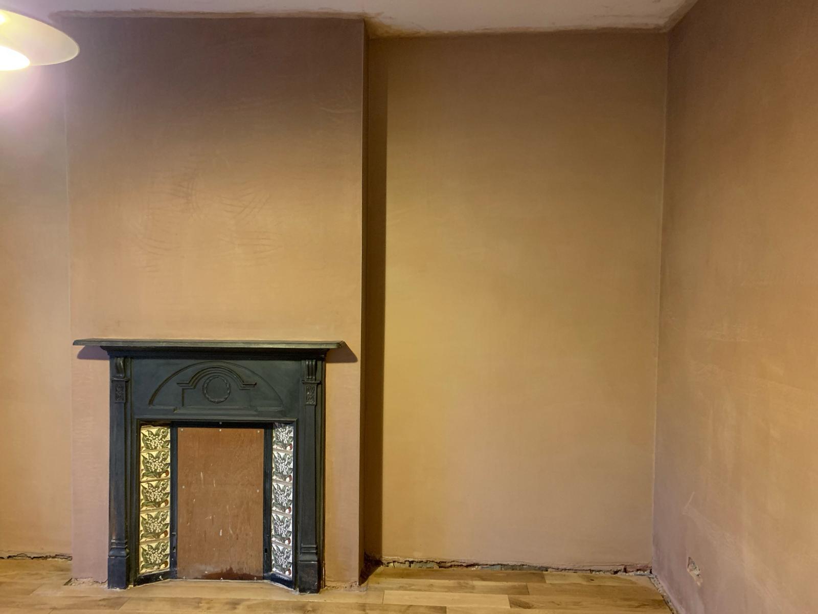 An image depicting a team of workers applying rendering material to the exterior of a building. The workers are using trowels and other tools to create a textured finish on the walls, showcasing the craftsmanship and attention to detail of a professional plastering and rendering company.