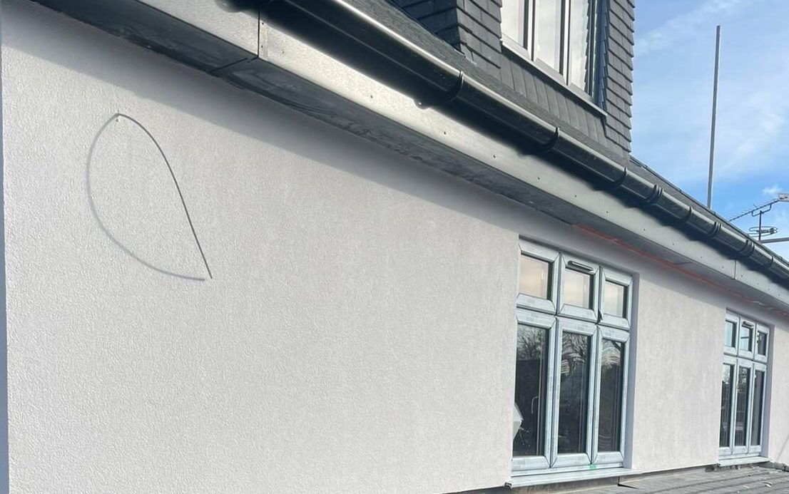 An image depicting a team of workers applying rendering material to the exterior of a building. The workers are using trowels and other tools to create a textured finish on the walls, showcasing the craftsmanship and attention to detail of a professional plastering and rendering company.